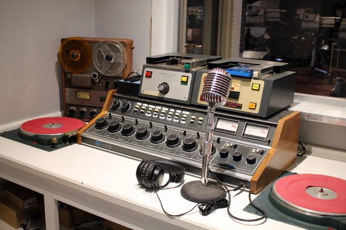 Estudio de radio con mesa de mezclas, micrófono y platos giradiscos
